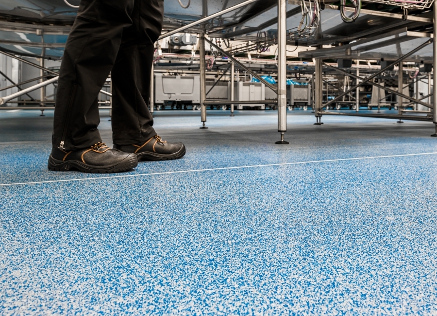 Eradur Struktur -  Person som står på blått golv i en produktionslinje